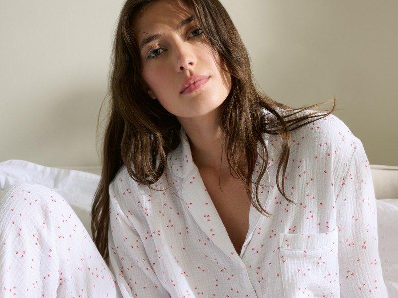 a woman laying in bed eating breakfast with a glass of orange juice